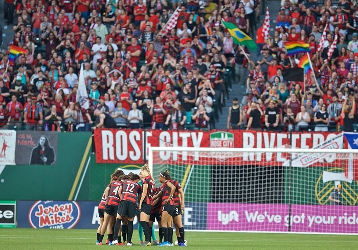 Portland Thorns on the field in 2019, backed by their supporters, the Rose City Riveters