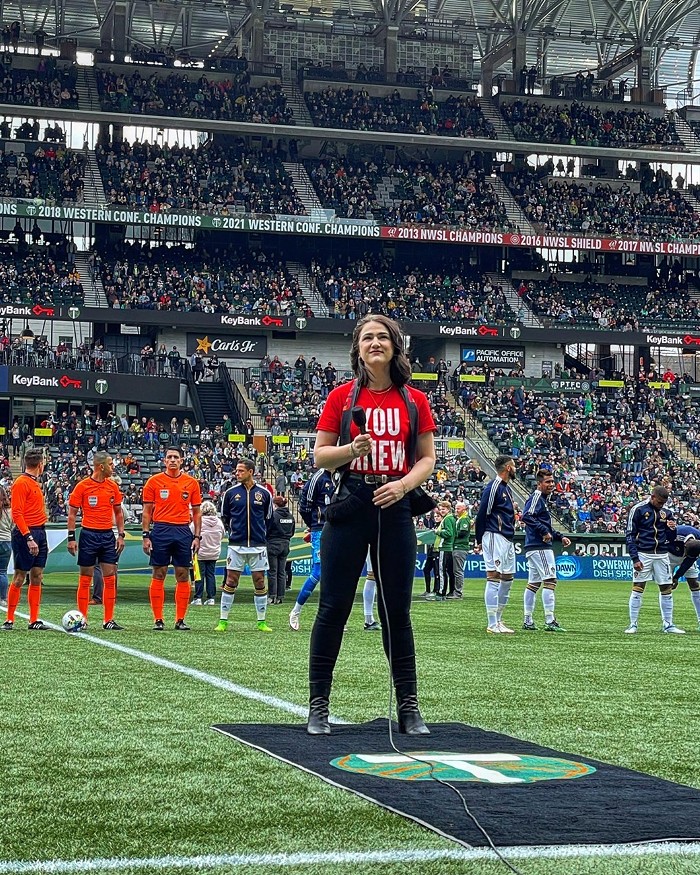 Madison Shanley sings the national anthem in a red T-shirt with the words YOU KNEW before the Portland Timbers match against the LA Galaxy.