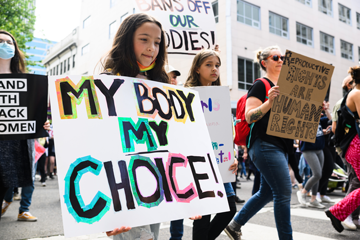 A young girl holding a sign reading My Body, My Choice